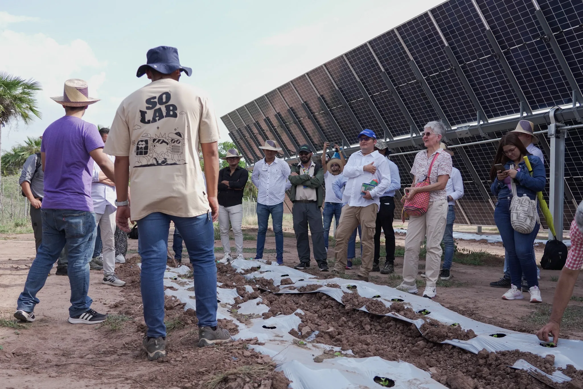 Grupo de personas recibiendo una charla o capacitación al aire libre junto a una instalación de paneles solares