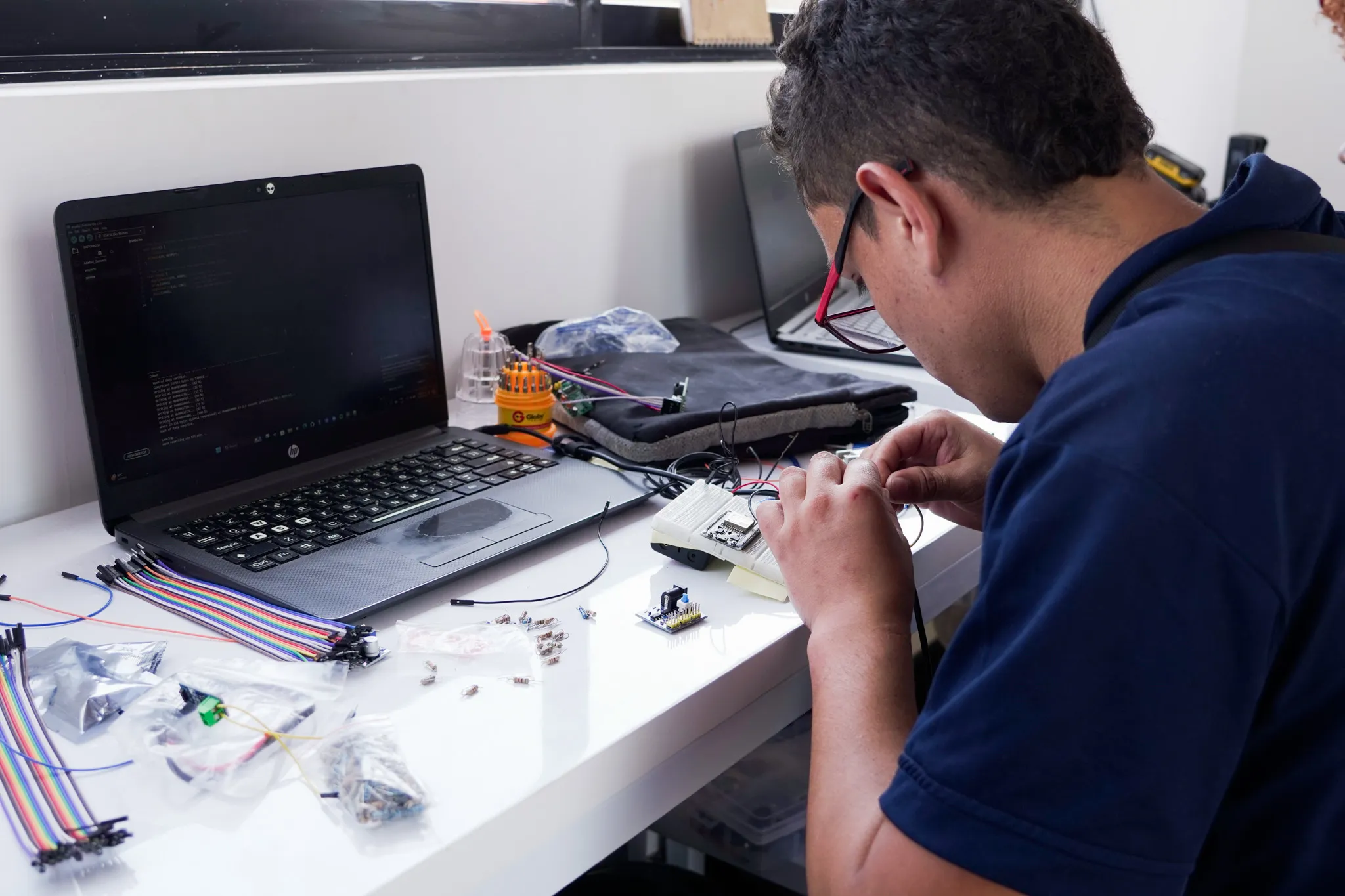 Estudiantes y jóvenes trabajando concentrados con computadoras en un taller tecnológico iluminado.
